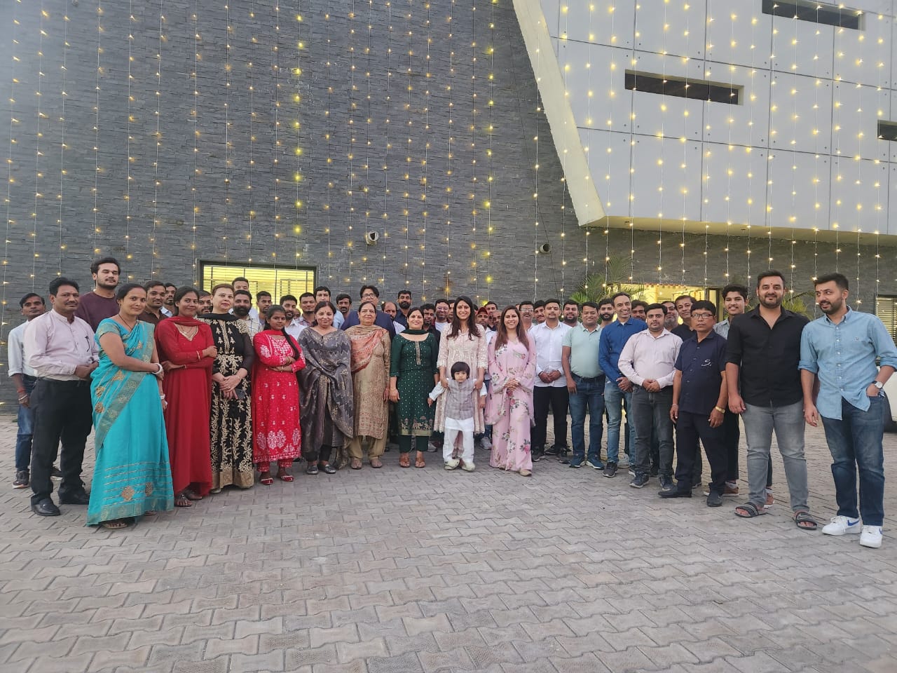 The Shivam International team gathered outside the facility, lit up with festive lights